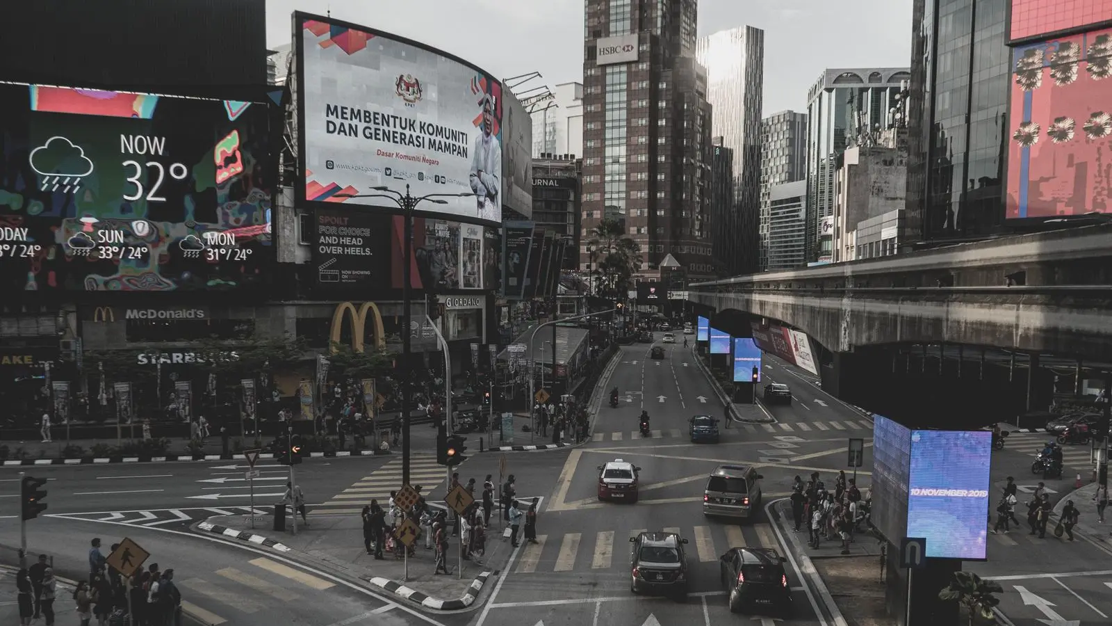 Vía urbana de noche con vallas y pantallas publicitarias iluminadas